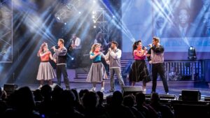 6 performers singing on a stage